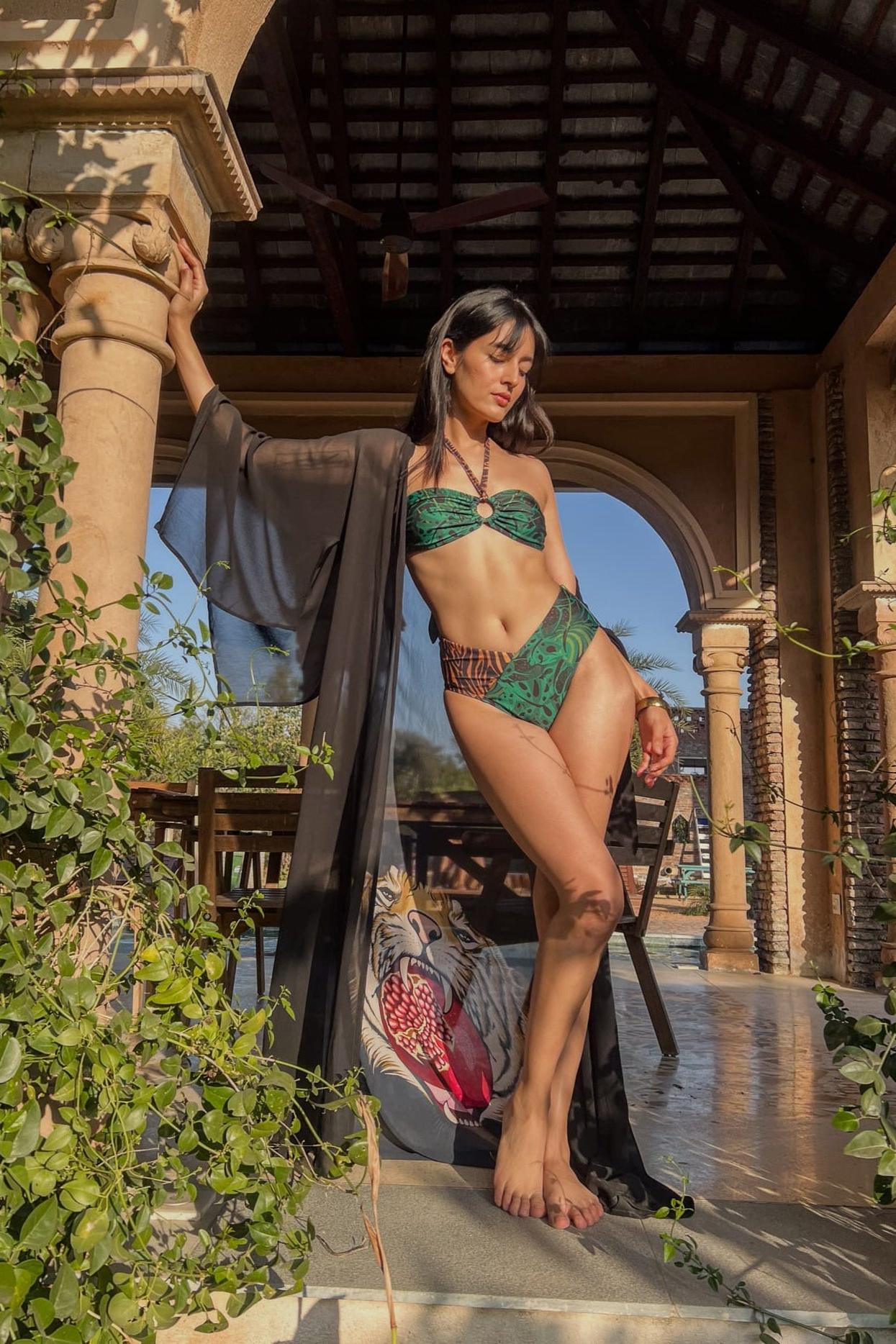 A model wearing a green V-cut bikini bottom with leaf and jungle print, standing in a tropical setting. swimsuit, swim dress, swimwear for ladies, swimsuit for ladies